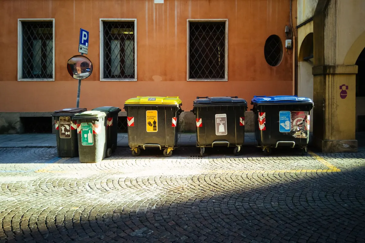 Bacs de tri et conteneurs à déchets d'une copropriété stationnés au pied de l'immeuble